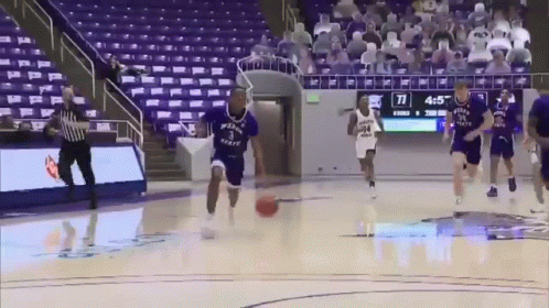 A Group Of Basketball Players Are Playing A Game Of Basketball On A Court With A Scoreboard Behind Them . GIF