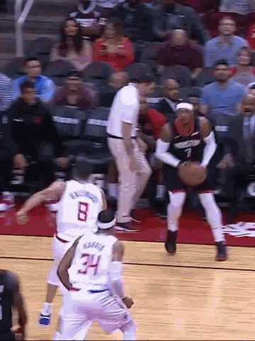 A Group Of Basketball Players Are Playing A Game On A Court With A Referee In The Background . GIF