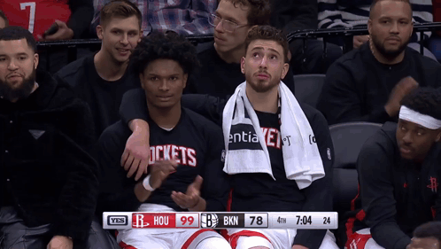 A Group Of Basketball Players Are Sitting In A Stadium With A Scoreboard That Says Hou 99 Bkn 78 GIF