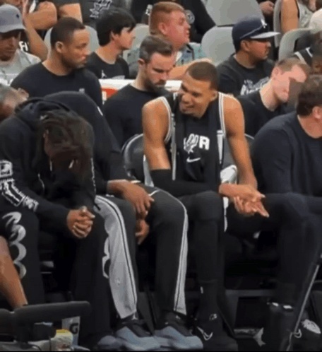 A Group Of Basketball Players Are Sitting In The Stands And One Of Them Is Wearing A Shirt That Says Spurs GIF