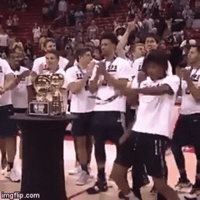 A Group Of Basketball Players Are Standing Around A Trophy With The Number 23 On Their Shirts GIF