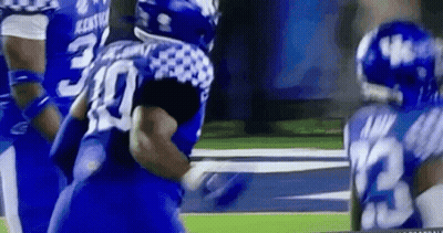 A Group Of Blue And White Football Players Are Playing A Game On A Field . GIF