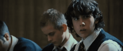 A Group Of Boys Are Sitting In A Classroom And One Of Them Has Curly Hair GIF