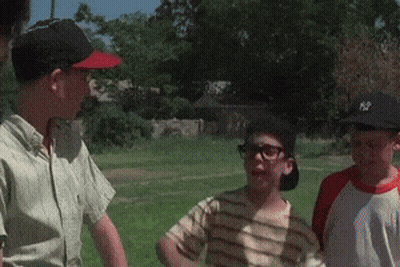 A Group Of Boys Are Standing In A Grassy Field And One Of Them Is Wearing A Ny Hat GIF