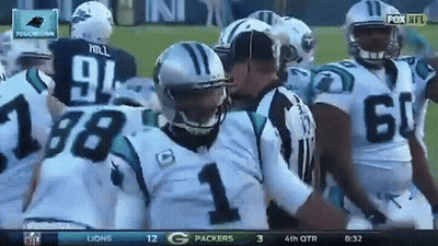 A Group Of Carolina Panthers Football Players Are Huddled Around A Referee GIF