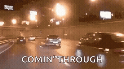 A Group Of Cars Are Driving Down A Highway At Night And The Words Comin ' Through Are Visible . GIF