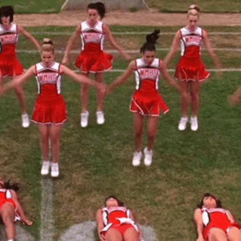 A Group Of Cheerleaders Are Performing On A Field And One Of Them Is Wearing A Hhs Uniform GIF