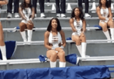 A Group Of Cheerleaders Are Sitting On A Bench In The Stands GIF