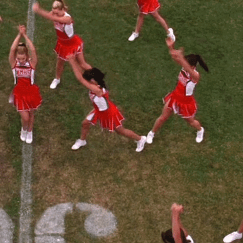 A Group Of Cheerleaders Are Sitting On The Grass In Front Of The Letter C. GIF