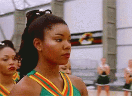 A Group Of Cheerleaders Are Standing In A Line And One Of Them Is Wearing A Green And Yellow Uniform GIF