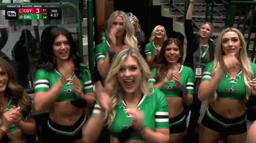 A Group Of Cheerleaders Are Standing In Front Of A Scoreboard Which Says Stanley Cup Playoffs On It GIF