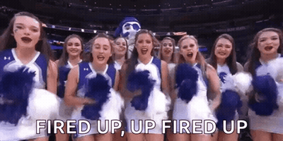 A Group Of Cheerleaders Are Standing Next To Each Other On A Basketball Court With A Mascot . GIF