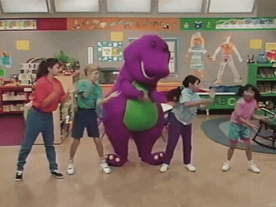 A Group Of Children Are Dancing Around A Purple Dinosaur In A Classroom With A Sign That Says Abc GIF