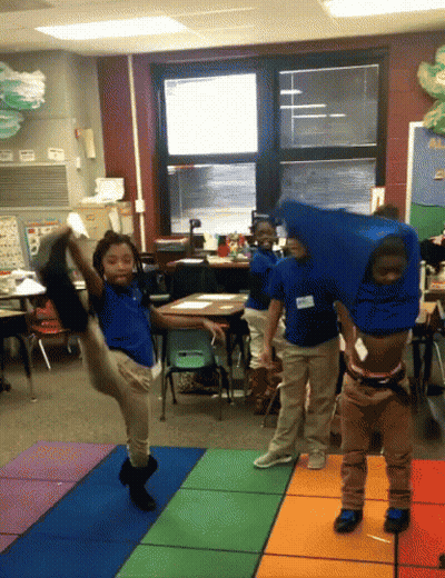A Group Of Children Are Dancing In A Classroom With One Wearing A Name Tag That Says ' Amanda ' On It GIF
