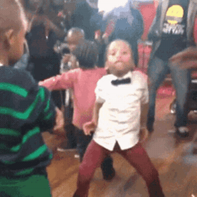 A Group Of Children Are Dancing In A Room With Adults . GIF