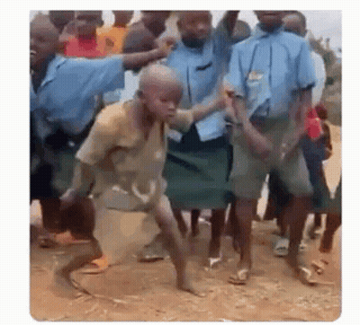 A Group Of Children Are Dancing In The Dirt In Front Of A Crowd . GIF