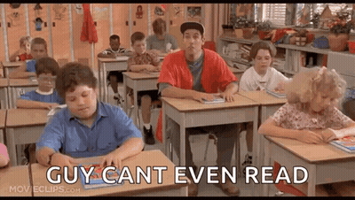 A Group Of Children Are Sitting At Desks In A Classroom With A Man Standing In The Middle Of The Room . GIF