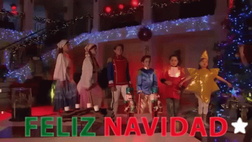 A Group Of Children Are Standing In Front Of A Christmas Tree With The Words Feliz Navidad Written Above Them GIF