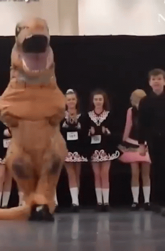 A Group Of Children Are Standing In Front Of A T-Rex Costume . GIF