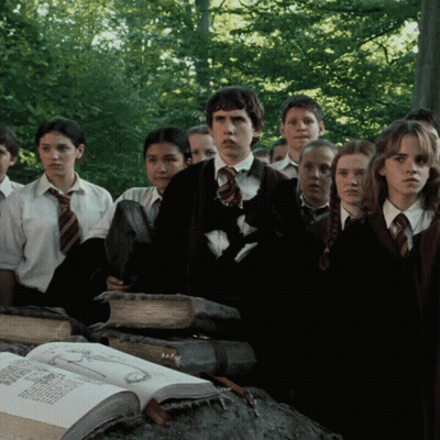 A Group Of Children In School Uniforms Are Standing Around A Large Book GIF