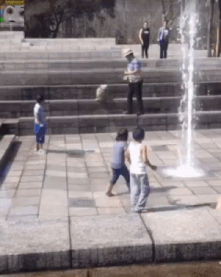 A Group Of Children Playing In Front Of A Water Fountain GIF