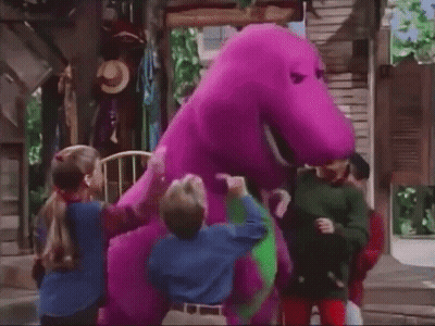 A Group Of Children Standing Around A Purple And Green Dinosaur . GIF
