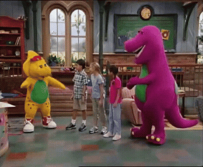 A Group Of Children Standing Around A Purple And Yellow Dinosaur GIF