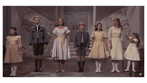 A Group Of Children Standing Next To Each Other On A Stage GIF