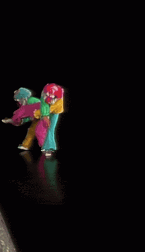A Group Of Clowns Are Dancing On A Stage In A Dark Room GIF