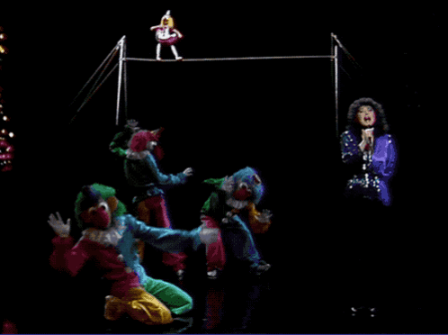 A Group Of Clowns Performing On A Stage With A Woman Singing In The Background GIF