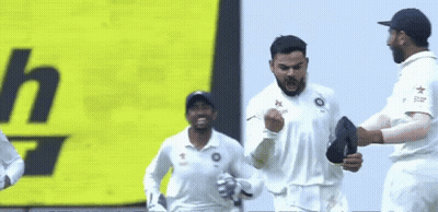 A Group Of Cricket Players Are Celebrating A Win In Front Of A Yellow Sign . GIF