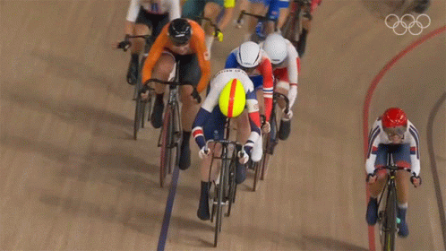 A Group Of Cyclists Are Racing On A Track With The Olympic Rings Visible In The Background GIF