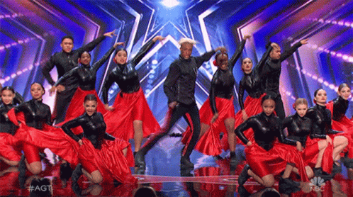 A Group Of Dancers Are Performing On A Stage And They Are Wearing Red Skirts . GIF