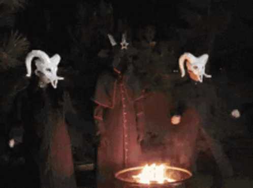 A Group Of Devils Standing Around A Fire At Night GIF