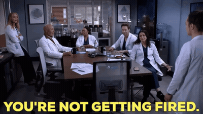 A Group Of Doctors Are Sitting Around A Table With The Words You 'Re Not Getting Fired GIF