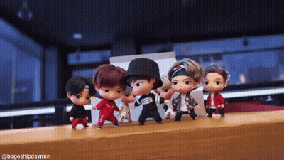 A Group Of Dolls Are Dancing Together On A Table . GIF