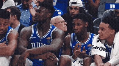 A Group Of Duke Basketball Players Are Sitting In The Stands GIF