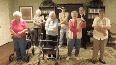 A Group Of Elderly People Are Standing In A Room Dancing GIF