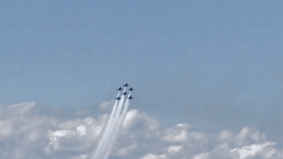 A Group Of Fighter Jets Flying Through A Blue Sky With Smoke Trails GIF