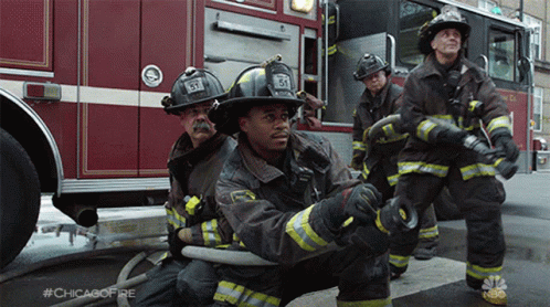 A Group Of Firefighters Are Kneeling In Front Of A Fire Truck With #Chicagofire Written On The Bottom GIF