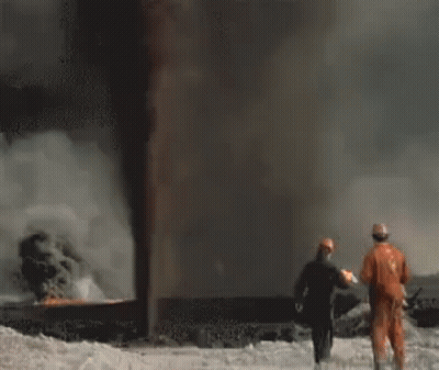 A Group Of Firefighters Are Standing In Front Of A Large Flame . GIF