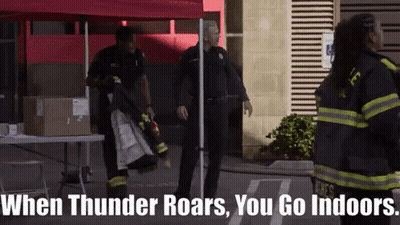 A Group Of Firefighters Are Standing In Front Of A Red Tent With The Words When Thunder Roars You Go Indoors GIF