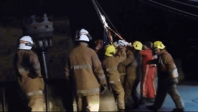 A Group Of Firefighters Wearing Yellow Helmets Are Standing In A Line GIF