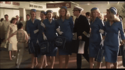 A Group Of Flight Attendants Are Walking In Front Of A Trans World Sign GIF
