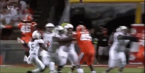 A Group Of Football Players Are Fighting On The Field . GIF