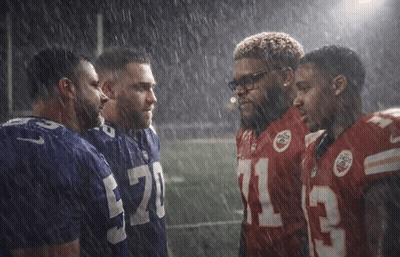 A Group Of Football Players Are Huddled Together In The Rain And One Of Them Has The Number 13 On His Jersey GIF