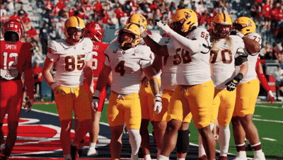 A Group Of Football Players Are Huddled Together With One Wearing The Number 4 GIF