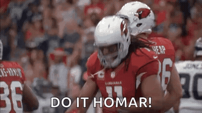 A Group Of Football Players Are Hugging Each Other On A Field . GIF