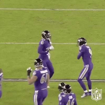 A Group Of Football Players Are Jumping In The Air On A Field During A Game . GIF