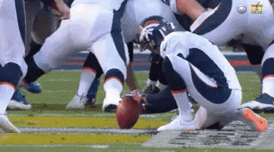A Group Of Football Players Are Kneeling Down On The Field Holding A Football . GIF